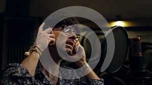 Close up shot of male singer singing lyrical composition into microphone in soundproof room