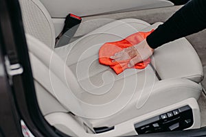 Close up shot of male worker cleans seat inside of car using microfibre cloth. Car detailing and valeting concept. Hand cleaning