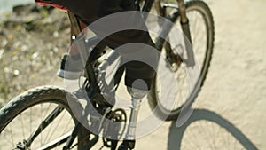 Close-up shot of man with artificial leg pedaling bike in nature