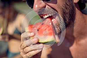 Close up shot of man eating watermelon fruit on beach. Couple on summertime holiday together. Holiday, togetherness, love,