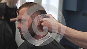 Close up shot of man getting trendy haircut at barber shop. Male hairstylist serving client, making haircut using