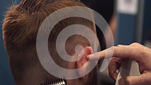 Close up shot of man getting trendy haircut at barber shop. Male hairstylist serving client, making haircut using