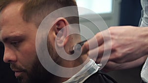 Close up shot of man getting trendy haircut at barber shop. Male hairstylist serving client, making haircut using