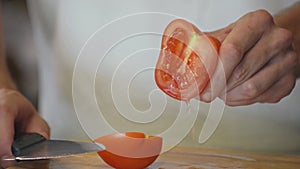 Close up shot of man hands slicing carrot and female hands cutting tomato on wooden cutting board for salad on the table