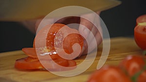 Close up shot of man hands slicing carrot and female hands cutting tomato on wooden cutting board for salad on the table