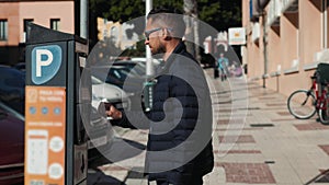 Close up shot of a man inserting a parking lot ticket at an automated pay machine. Cash Automated machines have taken