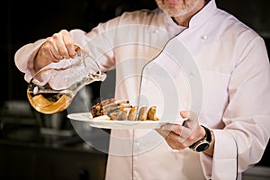 Close up shot of man pouring olive oil in prepared meal