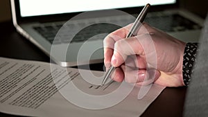 Close up shot of the man`s hand who leaves his signature on business document.