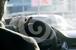 Close up shot of a man`s hands holding a car`s steering wheel. Driving safety in the city