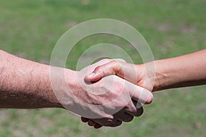 Close-up shot of man shake hands with a woman while standing in a garden. Concept of teamwork and partnership