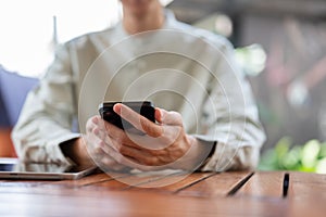 A close-up shot of a man using his smartphone at a table in a cafe
