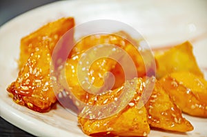 Close up shot of many delicious chunked sweet potatos topped in hot syrup photo