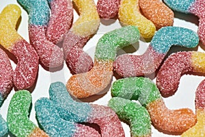 Close up shot of many tasty colorful sour sugar coated gummy worms isolated over white background