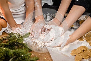 Close-up shot of many unrecognizable adult and child hands kneading yeast dough at kitchen table
