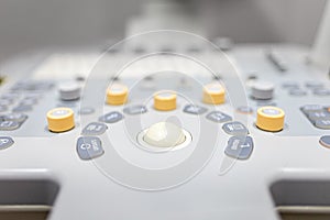 Close-up shot of medical ultrasound scanner with control bittons knobs sliders and ultrasonic transducer in background