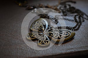 Close up shot of metal butterfly chain been put on a brown table with scratches