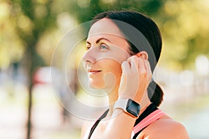 Close up shot of mid age woman wearing sportswear and her in ear buds.