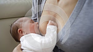 Close Up Shot Of Mother Sitting On Sofa At Home And Breastfeeding Baby