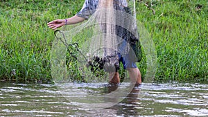 A close-up shot of a net with a fisherman walking down a river to catch fish, Thai equipment