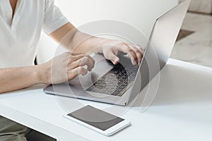 A close-up shot of person typing on computer laptop with the phone stand by ii