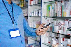 close up shot of Pharmacist busy using mobile phone at retail pharma medical store with copy space - concept of taking