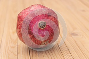 Close up shot of a pomegranate fruit on wooden background - Pomegranate benefits concept