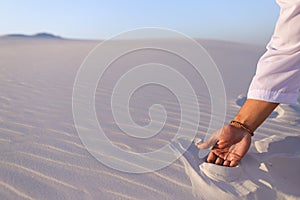 Close-up shot of portrait and hands of young Arab guy in sandy d