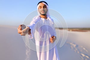 Close-up shot of portrait and hands of young Arab guy in sandy d