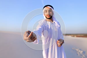 Close-up shot of portrait and hands of young Arab guy in sandy d