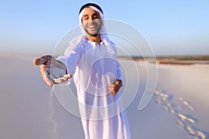 Close-up shot of portrait and hands of young Arab guy in sandy d