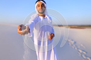 Close-up shot of portrait and hands of young Arab guy in sandy d