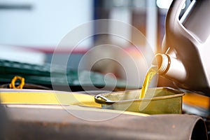 Close-up shot of pouring oil into the engine compartment Auto mechanic in car repair shop is pouring golden yellow engine oil in