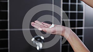 Close up shot of pouring shampoo to the woman`s hand in the shower, hair cosmetics, hydration and nutrition, hair care
