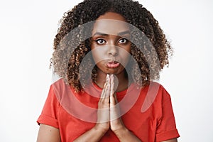 Close-up shot of pouting girl holding hands in pray and looking hopeful at camera as begging for favour or forgiveness photo