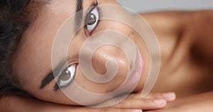 Close up shot of a pretty young wooman with smooth glowing skin relaxing on a white massage table.