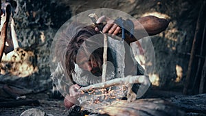 Close-up Shot of a Primeval Caveman Wearing Animal Skin Trying to make Fire with Bow Drill Method.