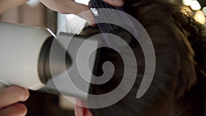 Close up shot of professional barber creates a stylish men's haircut with a hair dryer and a brush in his hands. Slow