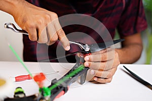 Close up shot professional engineer removing propeller by using spanner while repairning drone or uav at workplace - concept of