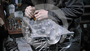 Close up shot of a professional mechanic disassembling engine block in car maintenance centre.