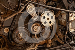 Close up shot of the pulley system and drive belt on a powerful diesel or gasoline used engine with parts of the car and vehicles