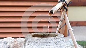 Close up shot of purification fountain with bamboo and stone basin