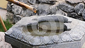 Close up shot of purification fountain with bamboo and stone basin