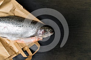 Close up shot of raw fresh rainbow trout on a black background on paper bag Preparations for cooking