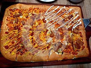 Close-up shot of a rectangular, thick-crust pizza featuring two distinct halves topped