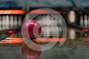 close-up shot of red bowling ball lying on alley under warm light