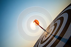 Close up shot red darts arrows in the target center on dark blue sky background. Business target or goal success and winner