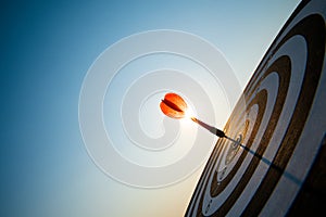 Close up shot red darts arrows in the target center on dark blue sky background. Business target or goal success and winner