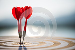 Close up shot red darts arrows in the target center on dark blue sky background. Business target or goal success and winner