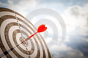 Close up shot red darts arrows in the target of dartboard center on dark blue sky background. Business target or goal success and