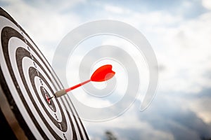 Close up shot red darts arrows in the target of dartboard center on dark blue sky background. Business target or goal success and